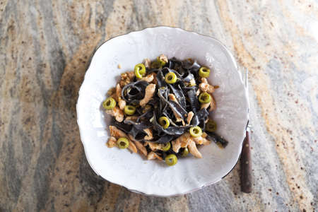 Black ink pasta with chicken breast and green olivesの写真素材
