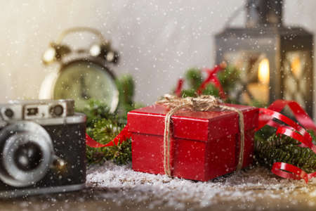 Red present box candle and retro camera with false snow Christmas composition
