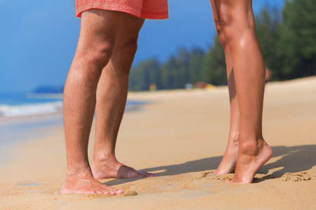 Legs of a kissing couple in love on a sea beachの写真素材