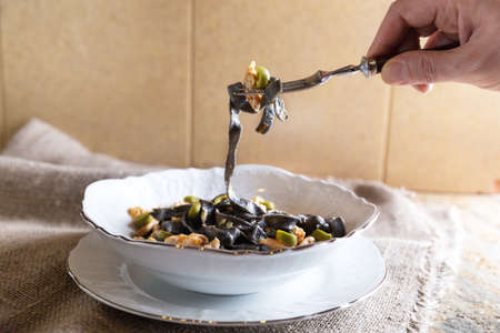 Black ink pasta with chicken breast and green olivesの写真素材