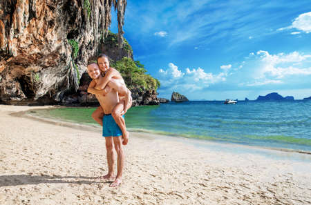 Happy couple in love boyfriend carrying his girlfriend in sea on a tropic beachの写真素材
