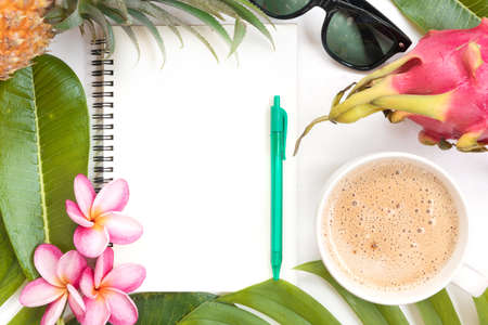 Tropical top view summer botanical concept still life sunglasses pineapple coffee cup notebook dragon fruit frame with monstera liana, vine, palm leaves and plumeria frangipani flower flat lay layoutの写真素材