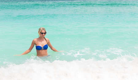Young pretty blond woman in blue bikini on a white tropical beachの写真素材