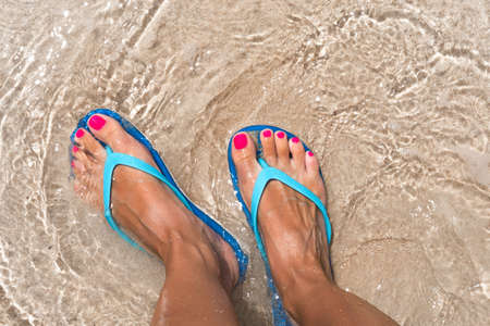 Woman legs stands in sea water on the tropic beachの写真素材