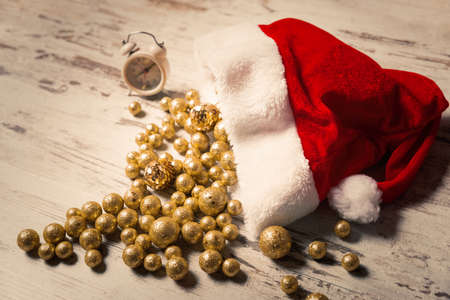Christmas composition with Santa hat full of golden sparkling baubles on wooden background holiday conceptの写真素材