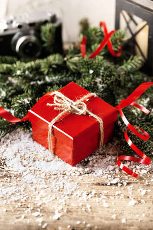 Red present gift box with camera and candle holder on wooden background Christmas New Year compositionの写真素材