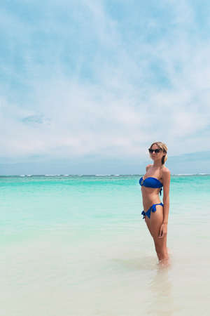 Young pretty blond woman in blue bikini on a white tropic beachの写真素材