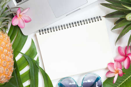 Tropical top view summer botanical concept still life laptop sunglasses pineapple notebook frame with monstera liana, vine, palm leaves and plumeria frangipani flower flat lay layoutの写真素材
