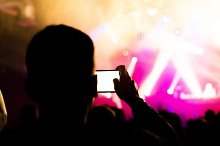 Man taking photo video by mobile phone of silhouettes crowd party concert music happyの写真素材