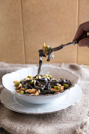 Black ink pasta with chicken breast and green olivesの写真素材