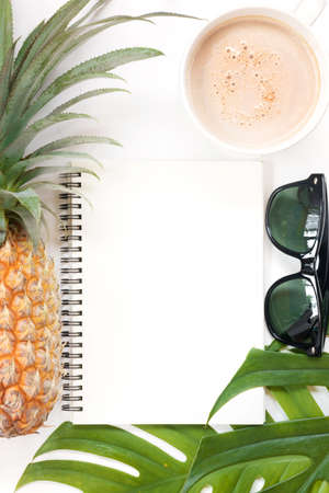 Tropical top view summer botanical concept still life sunglasses pineapple coffee cup notebook frame with monstera liana, vine, palm leaves and plumeria frangipani flower flat lay layoutの写真素材