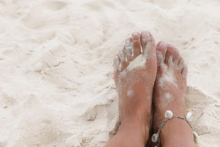 Woman legs in the white sand of sea beachの写真素材
