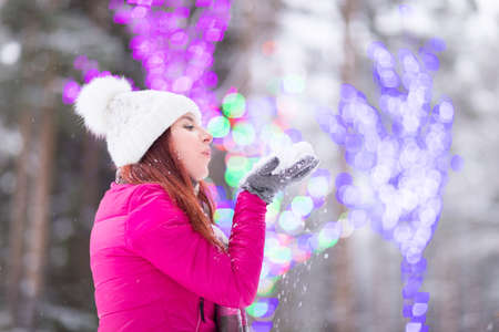 Happy winter women in park playing with snow and Christmas lights backgroundの写真素材