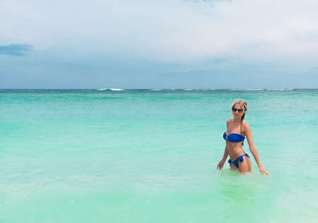 Young pretty blond woman in blue bikini on a white tropic beachの写真素材