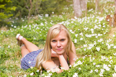 Pretty blonde woman on a spring meadow in blossom flowersの写真素材