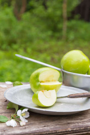 Fresh sweet juicy green apples with flowers on a wooden background in gardenの写真素材
