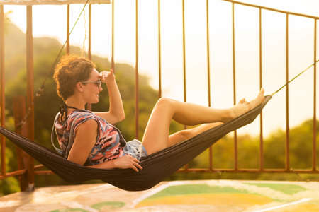 Young slim woman tropical exotic hammock in sunset lightsの写真素材
