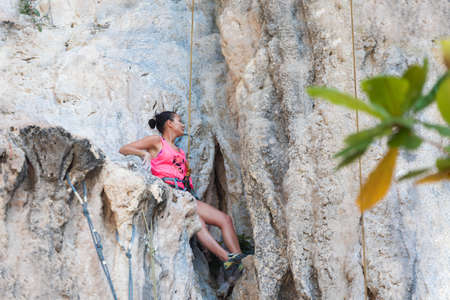 Young slim athletic woman climbing on a white karst rock mountain in Thailandの写真素材