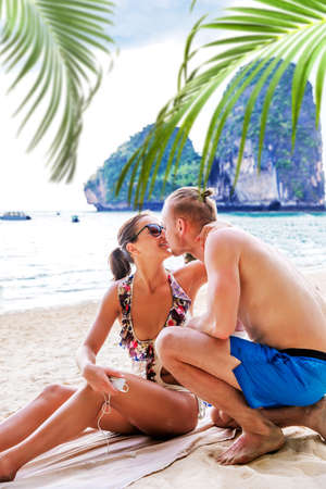 Happy couple in love boyfriend kissing his girlfriend in sea on a tropic beachの写真素材