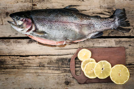 Fresh trout fish with spices on wooden backgroundの写真素材