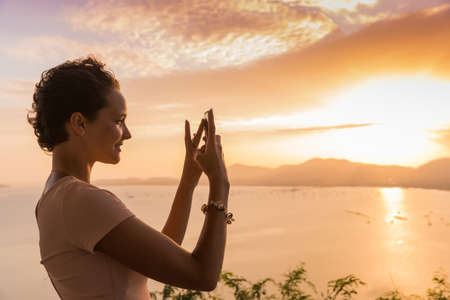 Young slim brunette woman with curly hair girl takes selfie photo pictures on observation deck view point on tropical asian Phuket island, Thailandの写真素材