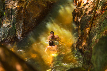 Man with action camera records his girlfriend swimming in a waterfall poolの写真素材
