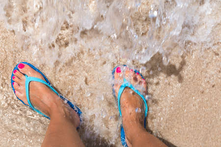 Woman legs stands in sea water on the tropic beachの写真素材