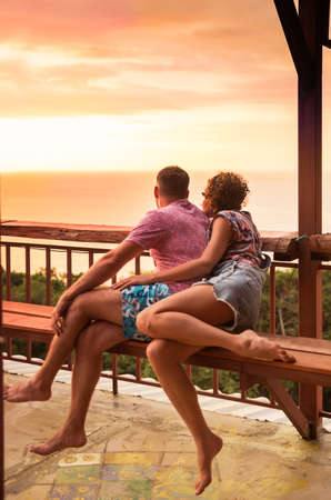 Young couple watches tropical exotic sunset from viewpointの写真素材