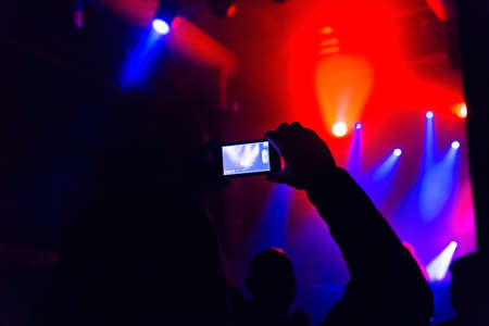 Man taking photo video by mobile phone of silhouettes crowd party concert music happyの写真素材