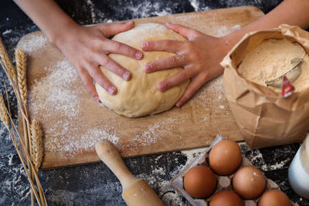 Knead the dough with the ingredients on a dark background