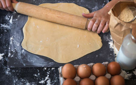 Knead the dough with the ingredients on a dark background