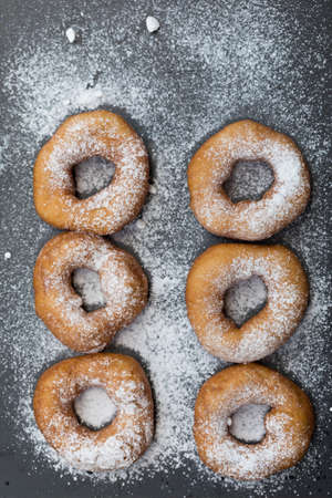 Homemade donuts with icing sugar powder on a wooden backgroundの写真素材