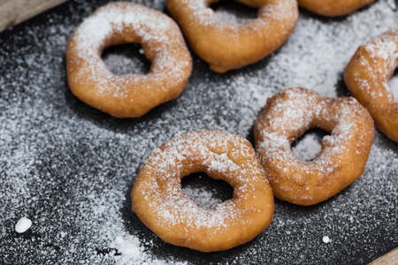 Homemade donuts with icing sugar powder on a wooden backgroundの写真素材