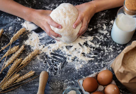 Knead the dough with the ingredients on a dark backgroundの写真素材