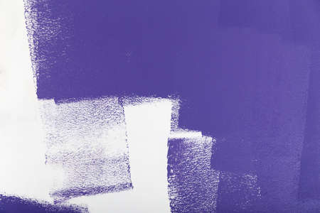 Violet paint roller on a white wallの写真素材