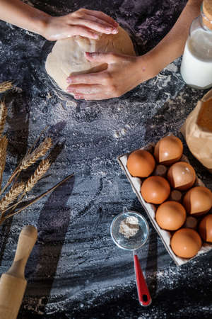 Knead the dough with the ingredients on a dark background