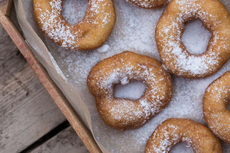 Homemade donuts with icing sugar powder on a wooden backgroundの写真素材
