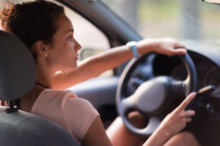 Young pretty woman curly hair drives car country