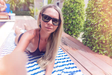 Young pretty blonde woman with smartphone taking selfie photo or speak by video chat