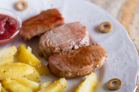 Backed tuna fish fillet with potatos on plate on stoneの写真素材