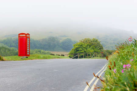 Fog with classical red telephone booth box in misty English countryside, United Kingdom