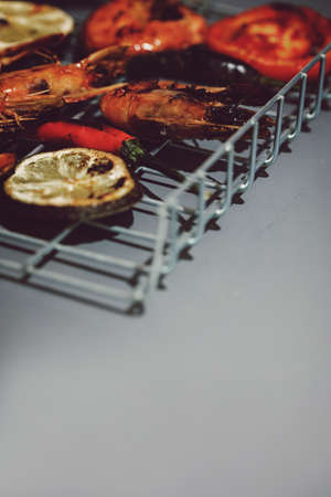Fresh grilled prawn shrimps on metal grid and grey background