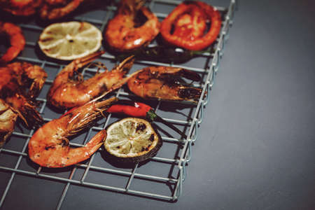 Fresh grilled prawn shrimps on metal grid and grey background