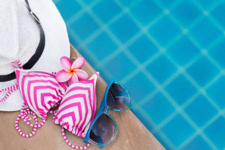 Sunglasses orchid flower and colorful swimwear near swimming pool