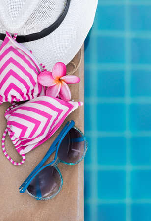 Sunglasses orchid flower and colorful swimwear near swimming poolの写真素材