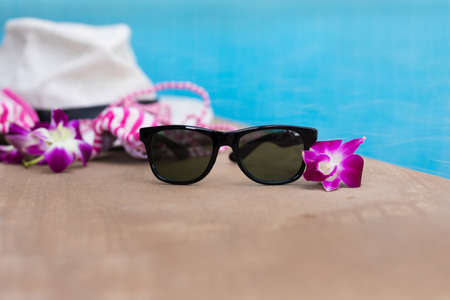 Sunglasses orchid flower and colorful swimwear near swimming poolの写真素材
