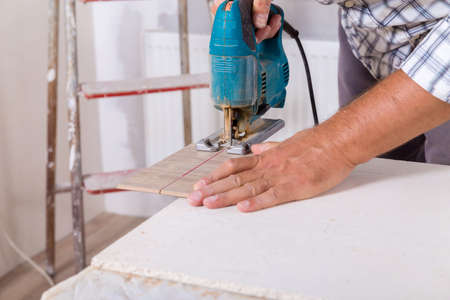 Installing laminate flooring. Carpenter cut parquet floor board with electric jigsaw.の写真素材
