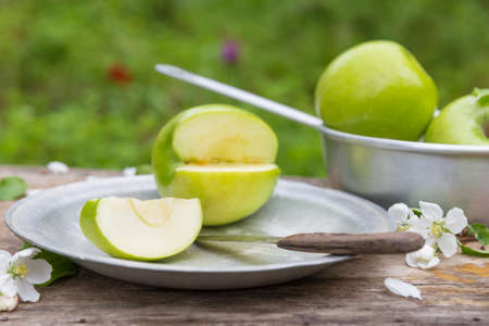 Fresh sweet juicy green apples with flowers on a wooden  in gardenの写真素材