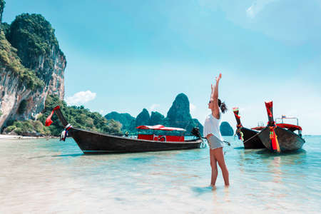 Young woman with thailand longtail boats on a beachの写真素材