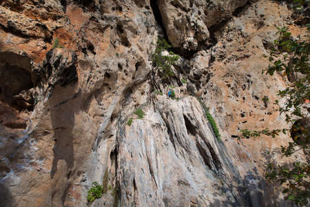 Young man rock climbing on a karst limestone white mountain in Thailandの写真素材
